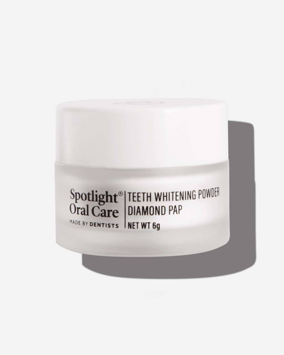 A close-up shot showcases a cylindrical jar of Spotlight Oral Care teeth whitening powder