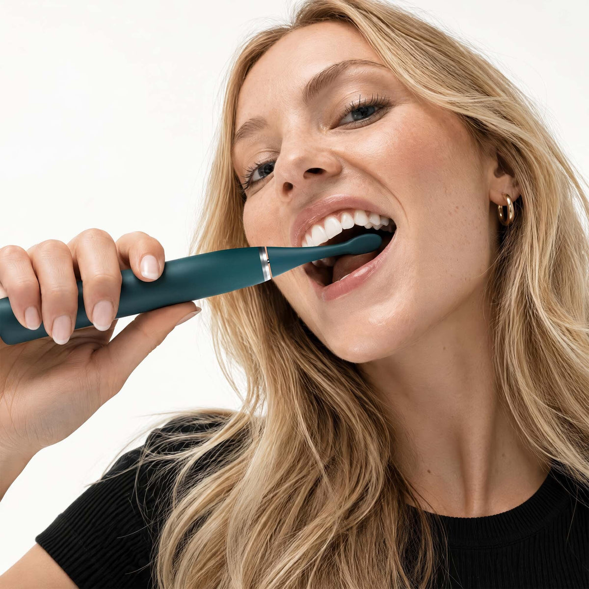 Woman brushing with the limited edition Emerald Green Sonic Pro