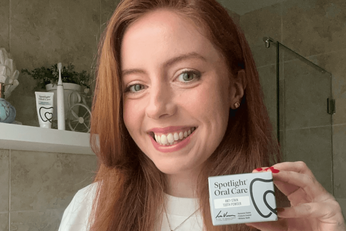 Smiling woman holding a small, white box labeled Spotlight Oral Care	